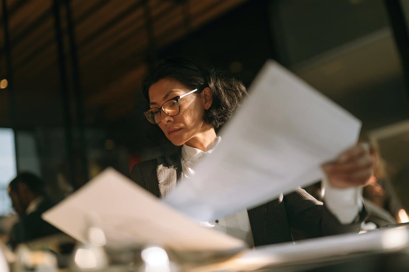 A finance lead reviewing printed reports at her desk.